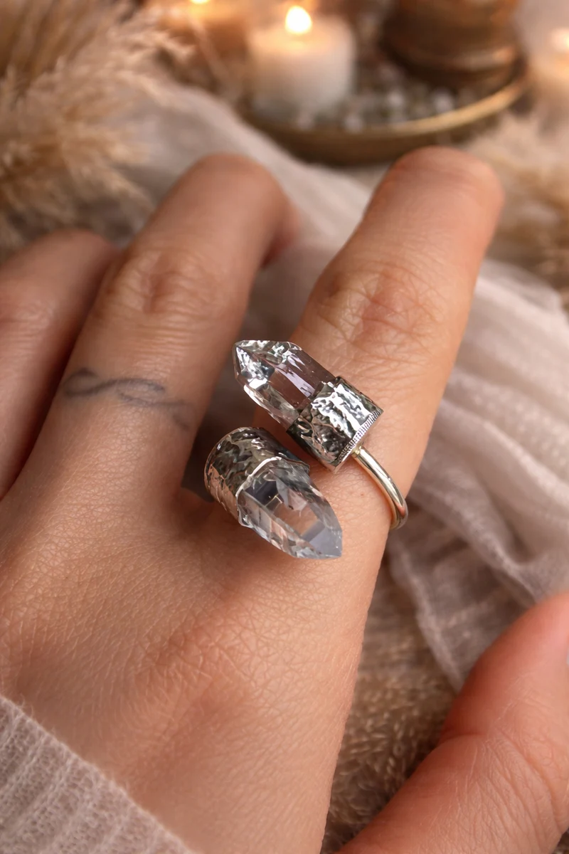 Close-up of a hand wearing two crystal rings with a soft, blurred background.