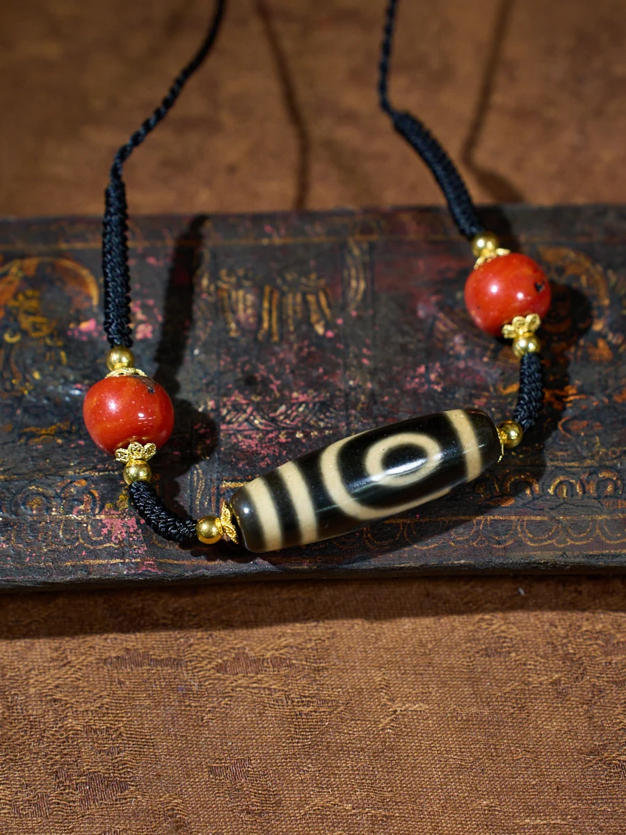 Necklace with red beads and a black and white bead on an old book