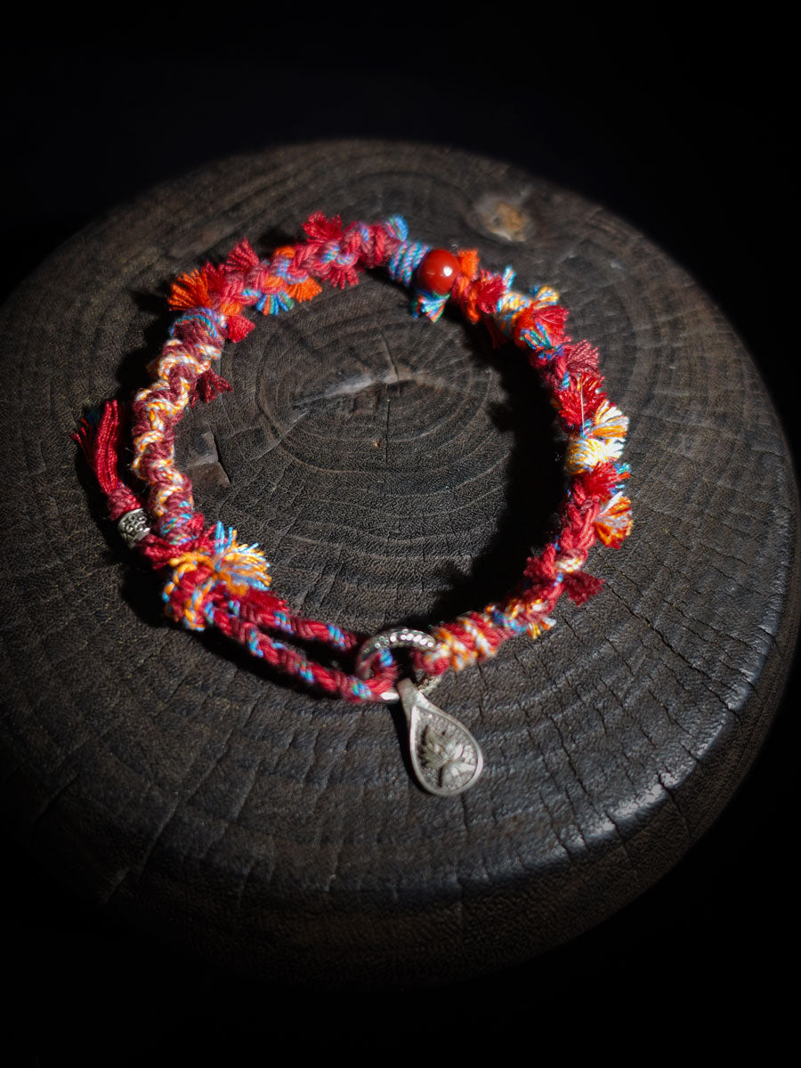 Colorful beaded bracelet with a silver charm on a dark surface